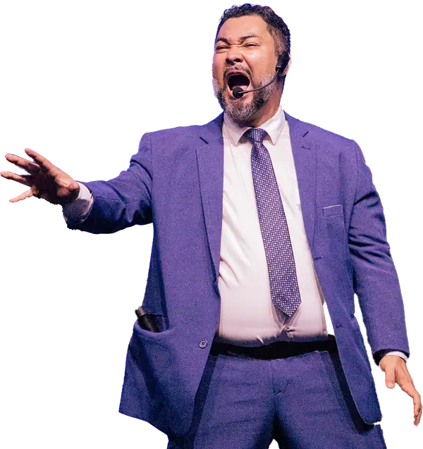 Clayton Yaso de terno azul e microfone de cabeça, de braço estendido e boca aberta, em plena interpretação no palco.